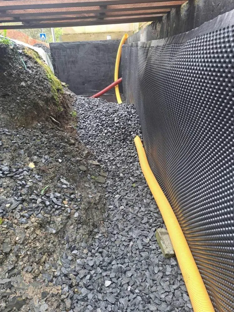 Pose d'un drain et d'une membrane contre un mur enterré